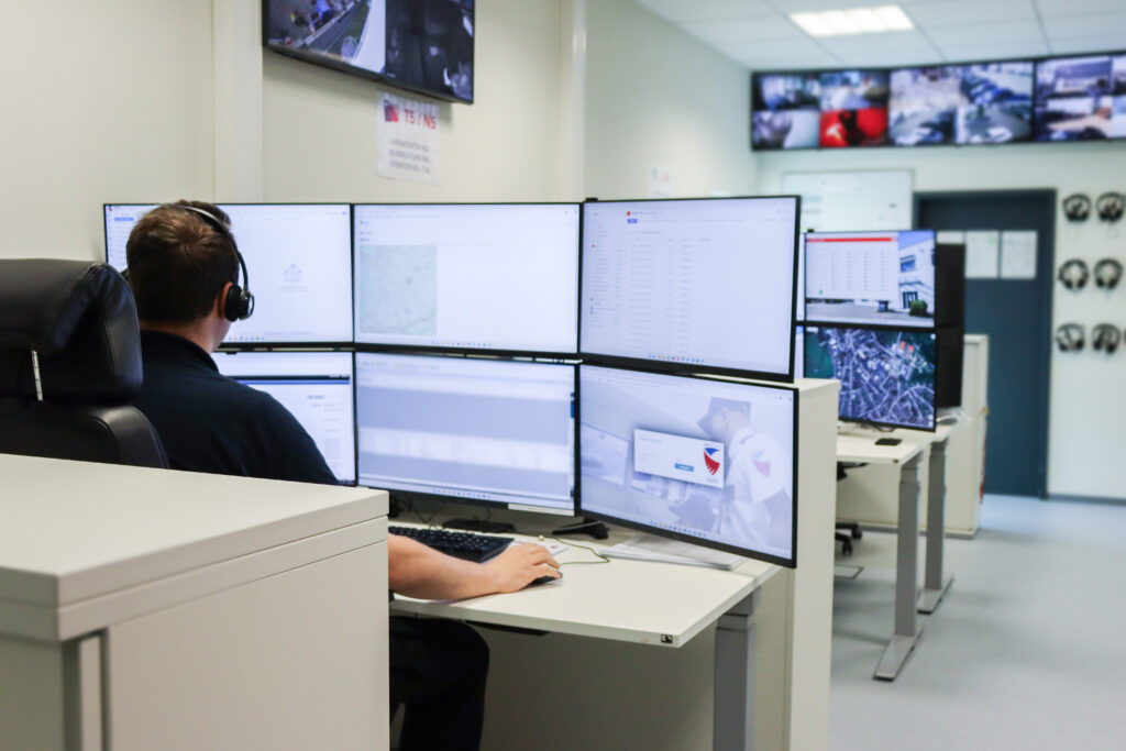 Sicherheitsmitarbeiter von Pond Security sitzt mit Headset an einem Arbeitsplatz mit mehreren Monitoren in der NSL-Überwachungszentrale.